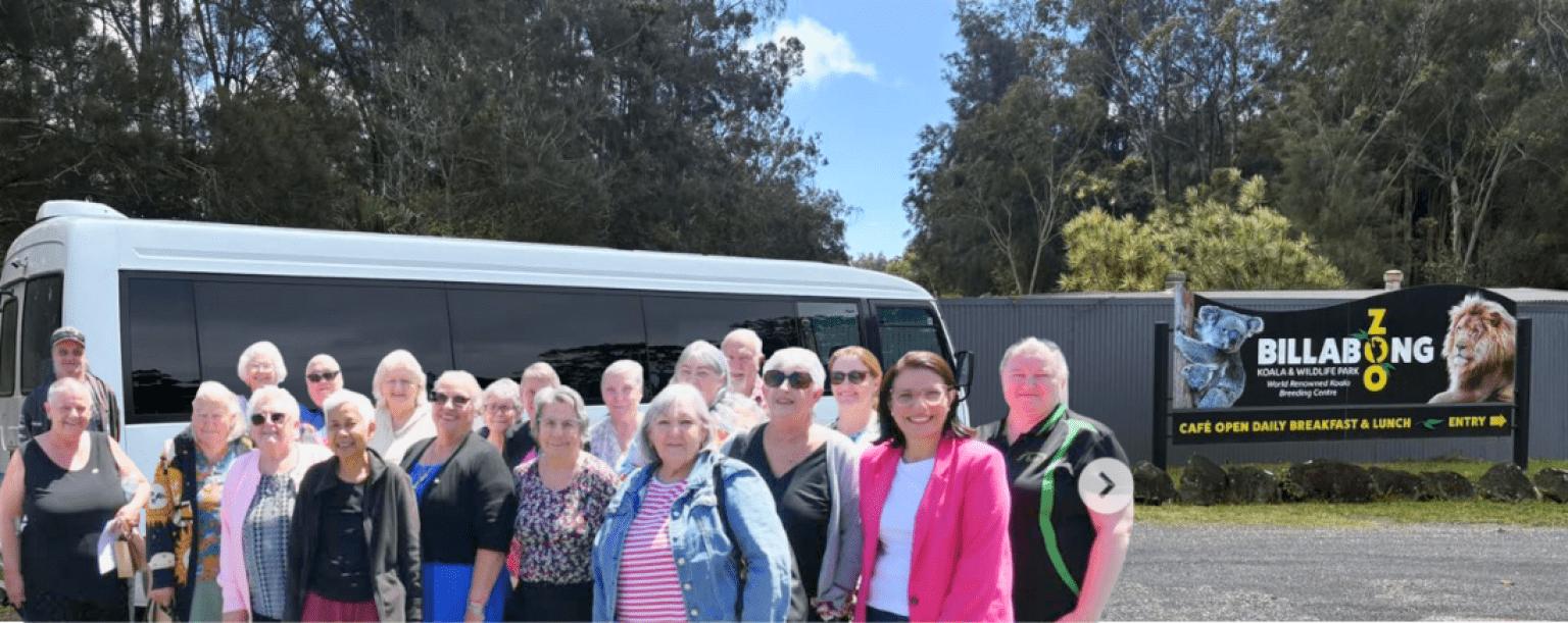 A group of travellers stand outside their bus at the entry to Billabong Zoo